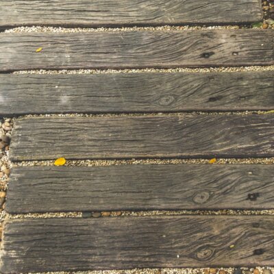 Verwitterte Holzbohlen eingebettet in Kies als Gartenweg © Shutterstock - chanin1991