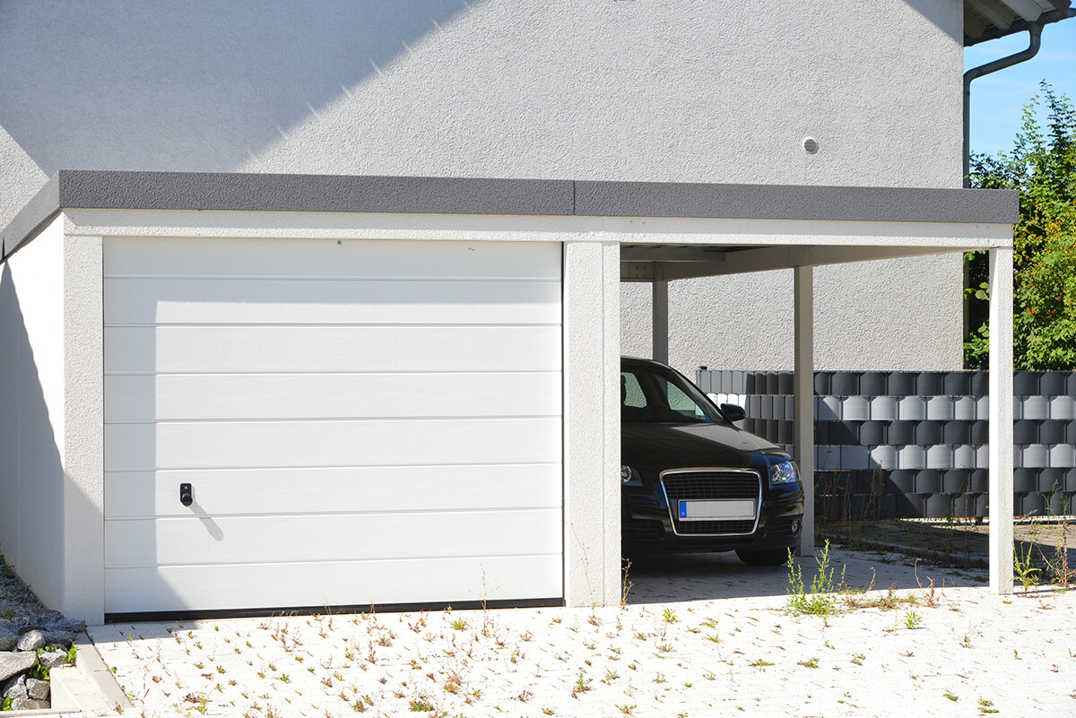 Moderne Beton-Garage mit Automatik-Tor und angebautem Carport in der Hauszufahrt
