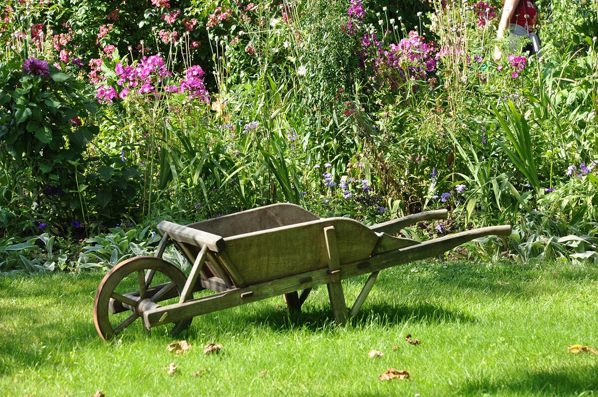 Holzschubkarre als Gartendeko im Naturgarten
