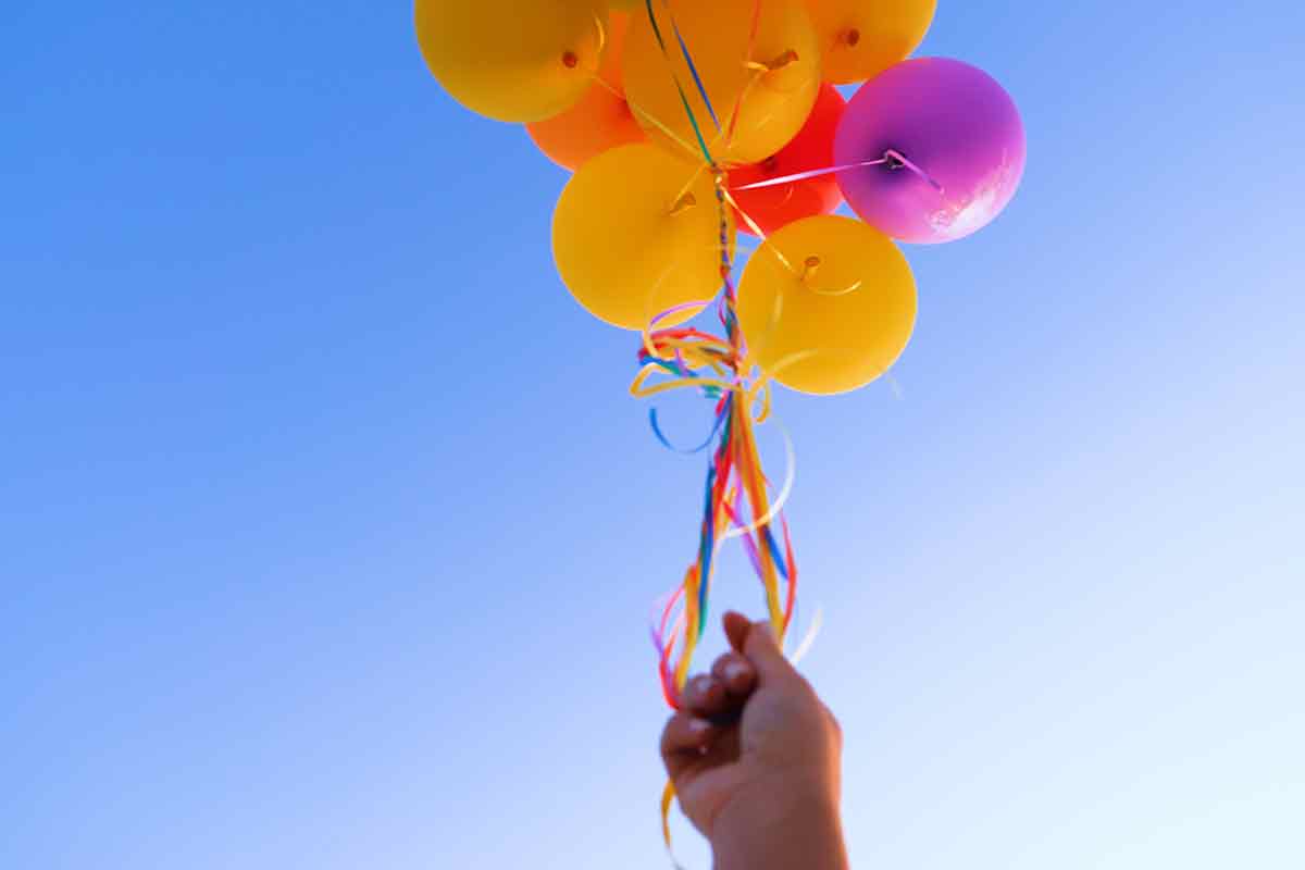 Hand hält bunte Luftballons