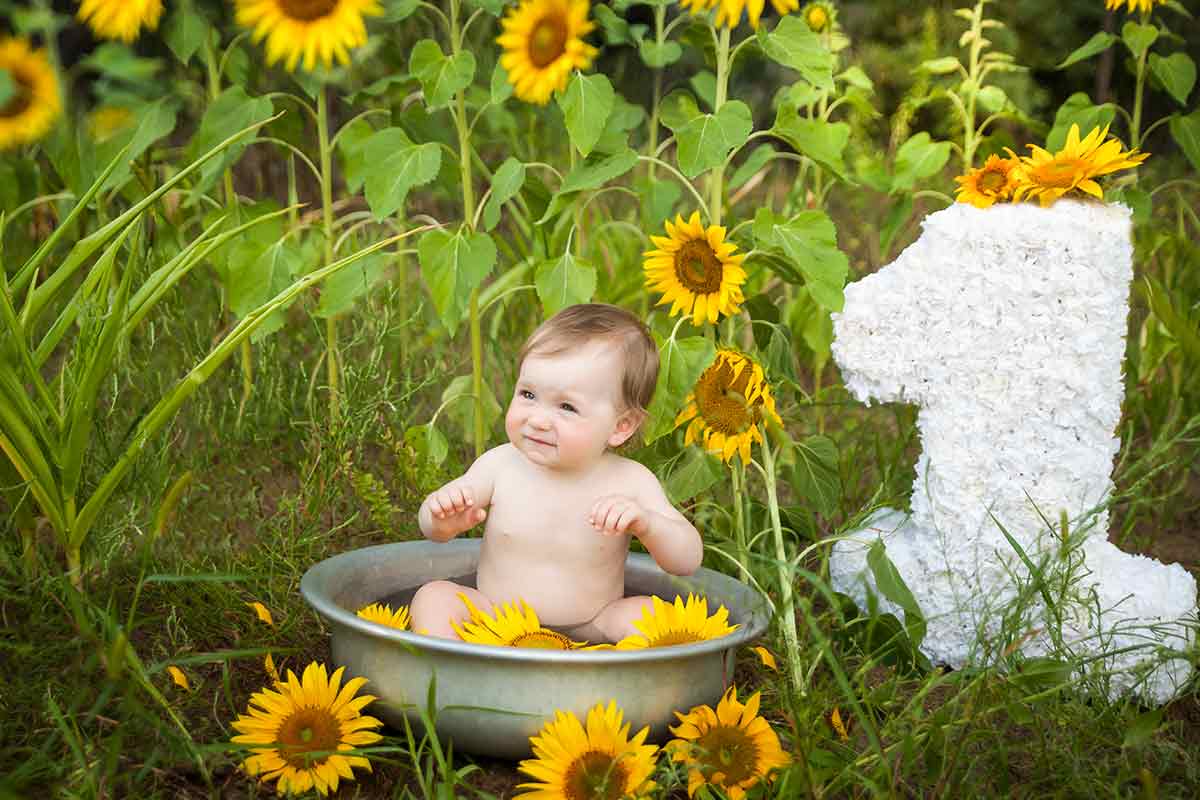 Baby in Planschbecken mit Sonnenblumen