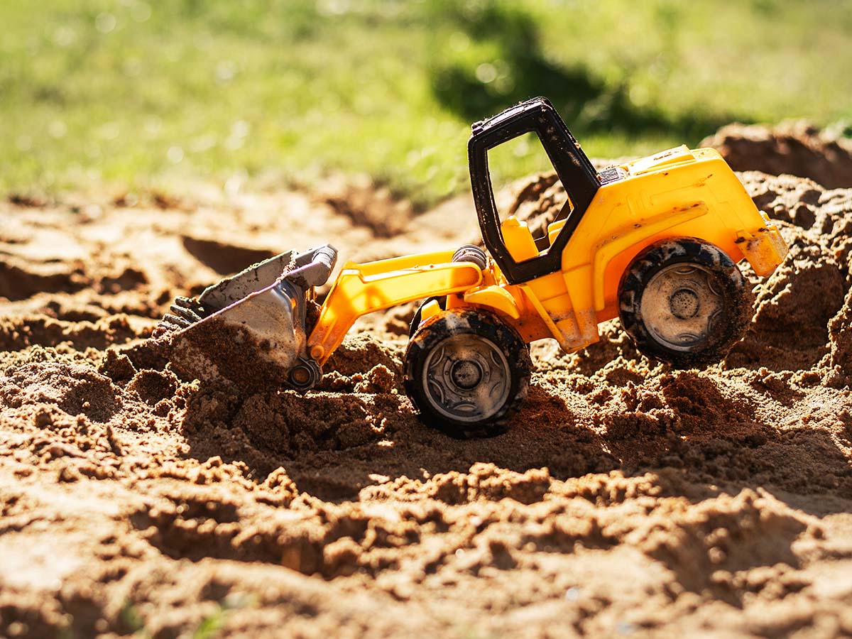 Spielzeug Bagger im Sandkasten auf Kinder-Spielplatz