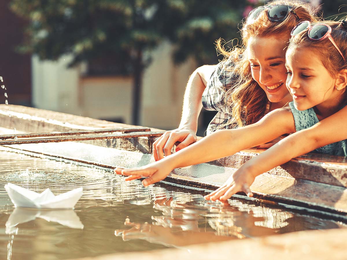 Mutter spielt mit Tochter auf Wasser-Spielplatz