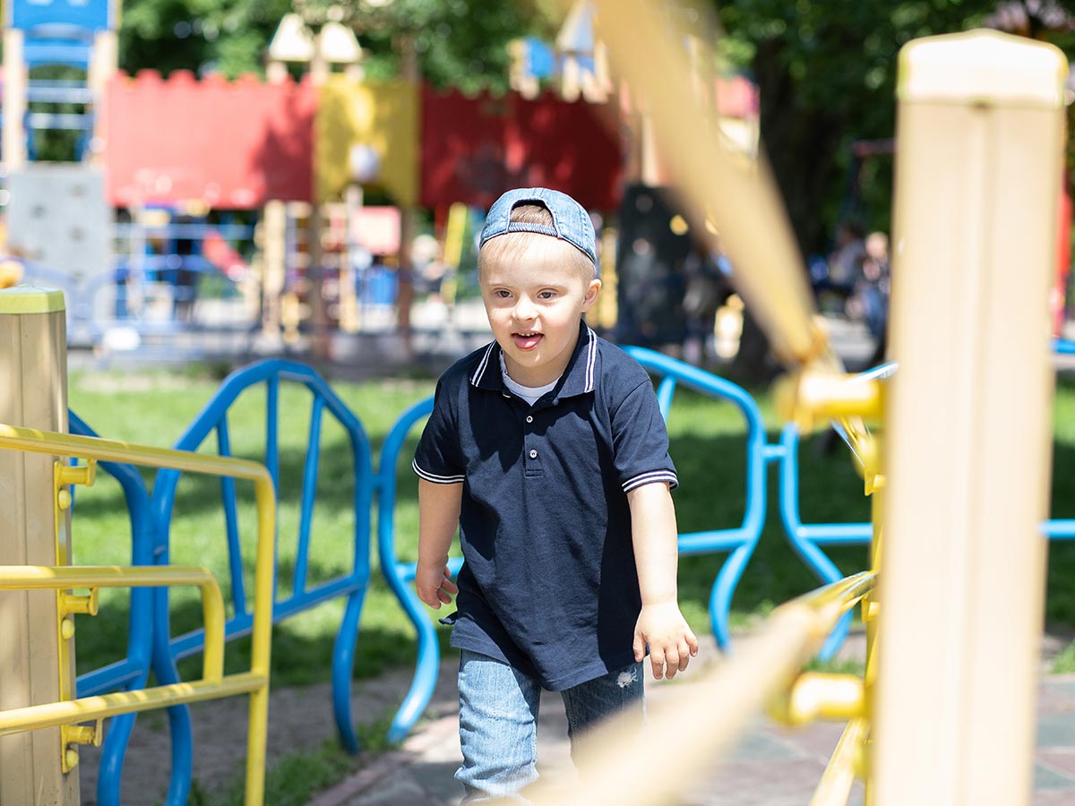 Kind mit Down-Syndrom spielt auf inklusivem Kinder-Spielplatz