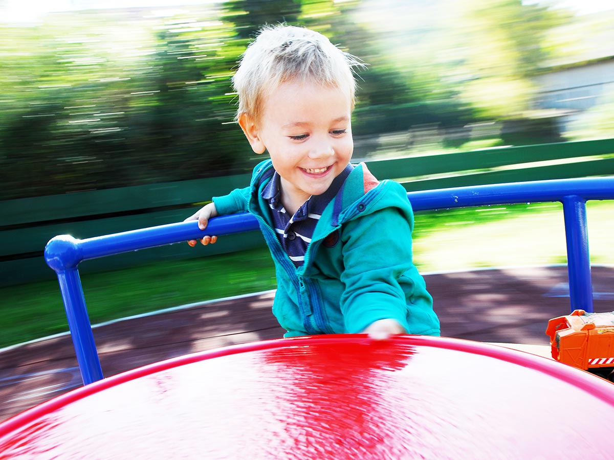 Junge spielt in Karussel auf Kinder-Spielplatz