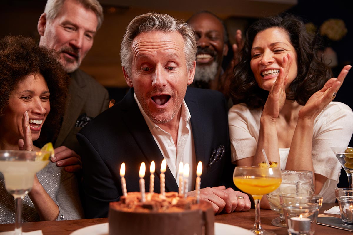 Mann pustet Kerzen zum 50. Geburtstag aus