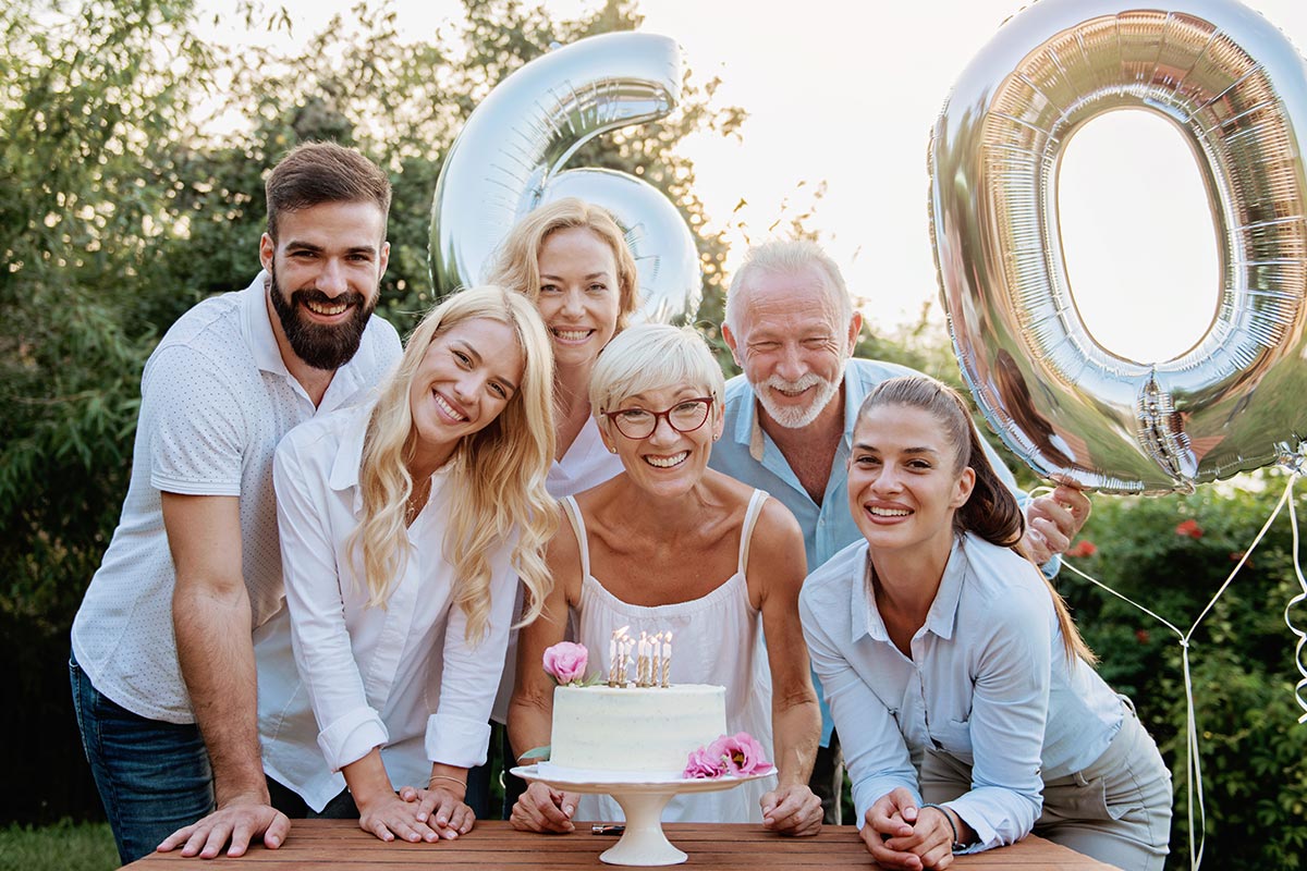 Frau feiert mit Torte und Freunden 60. Geburtstag im Garten
