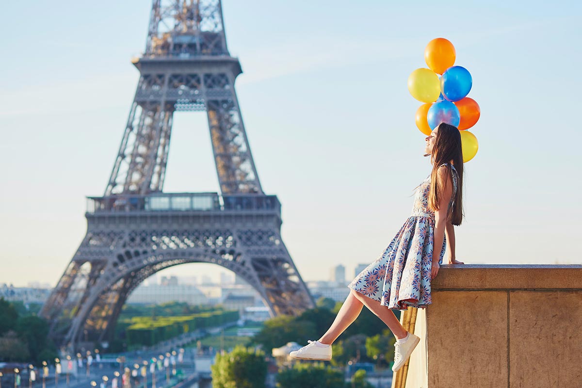 Junge Frau mit Luftballons zum Geburtstag vor Eiffelturm