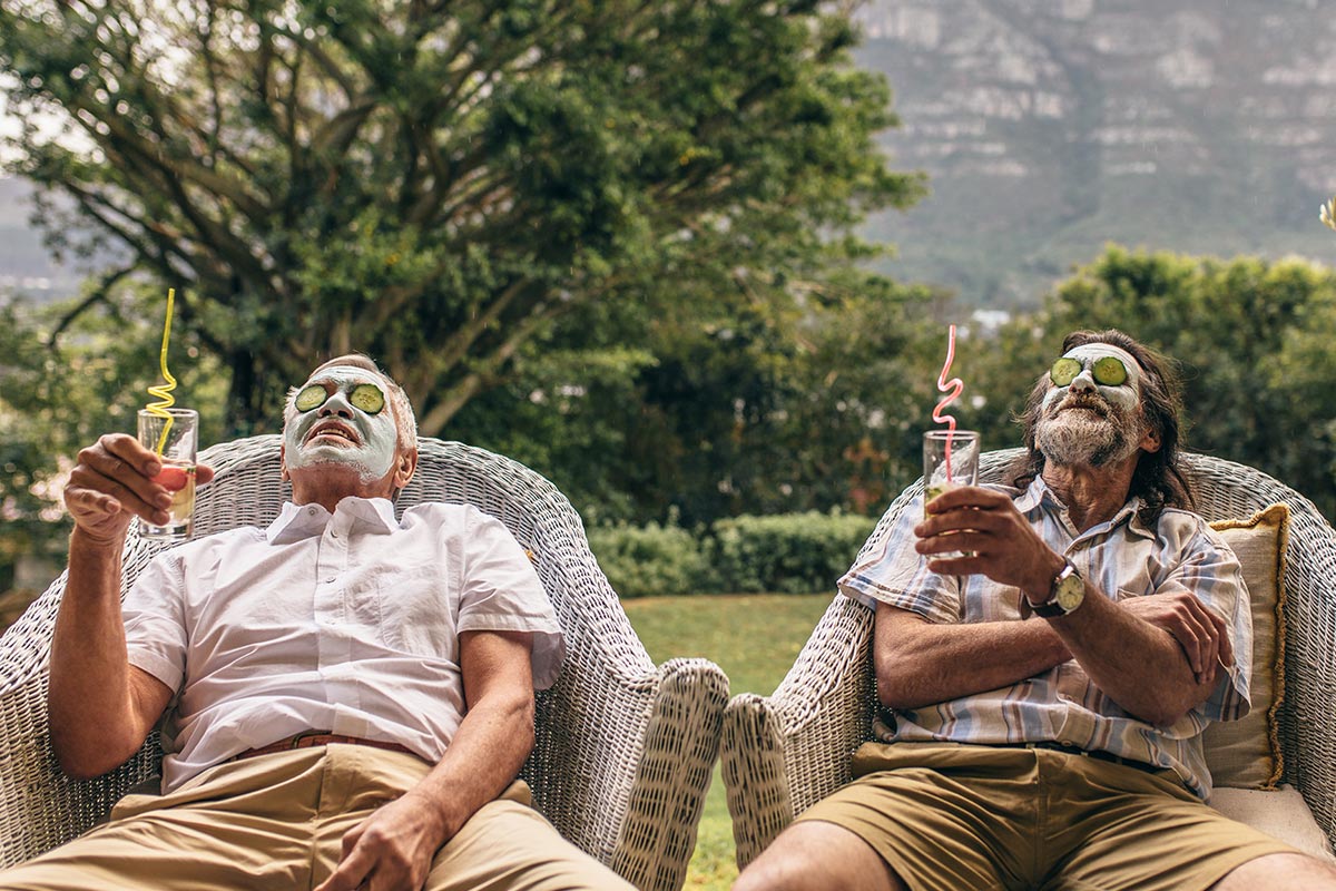 Zwei ältere Männer entspannen mit Cocktail und Gesichtsmaske in Natur