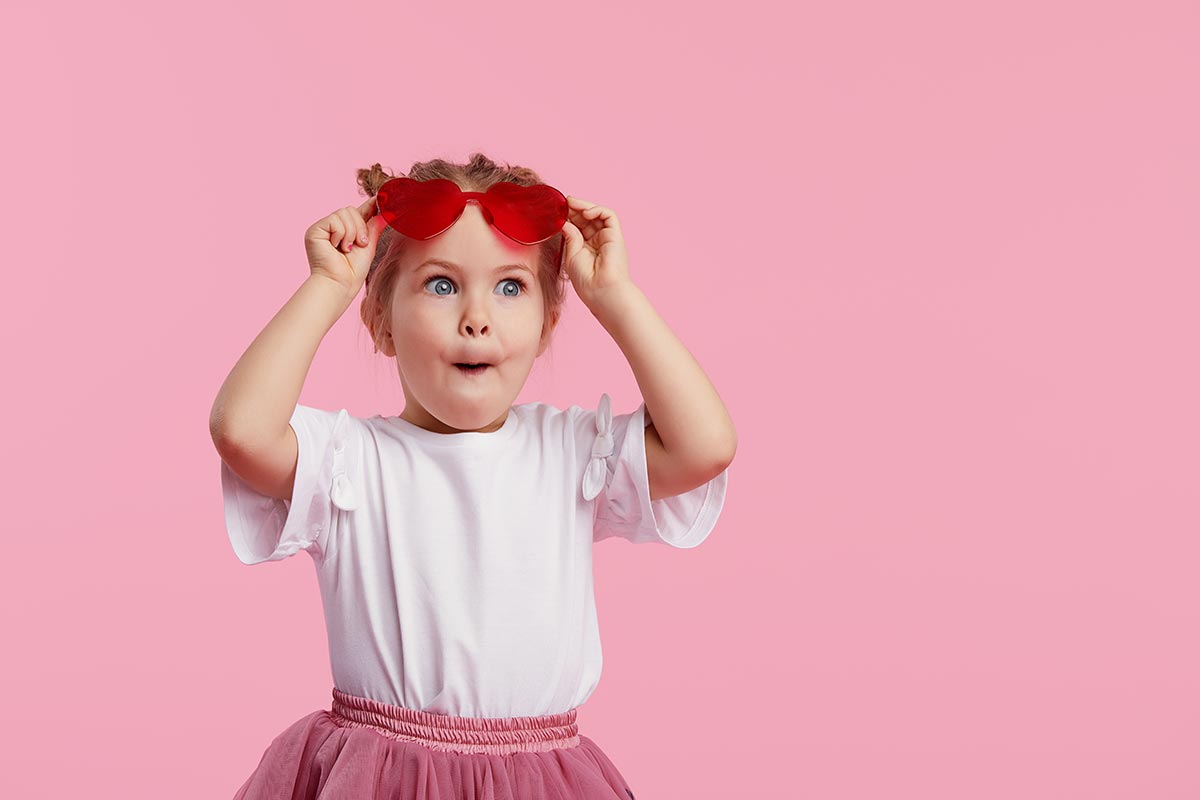 Kleines lustiges Mädchen vor rosa Hintergrund