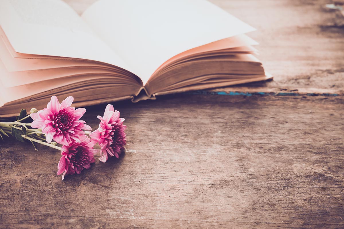 Offenes Buch auf Holztisch mit Blume und Liebesgedichten