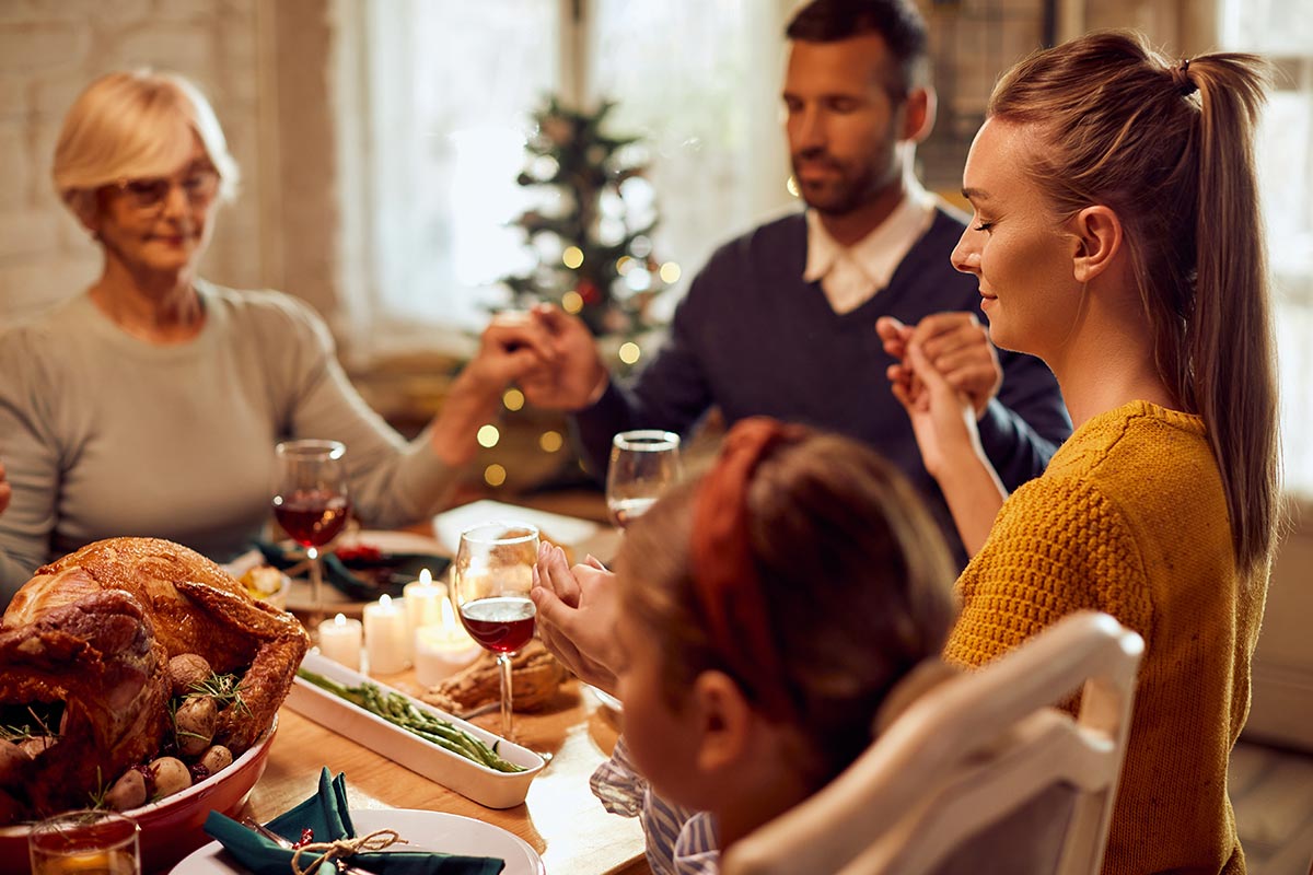 Familie betet zusammen am Weihnachtstisch