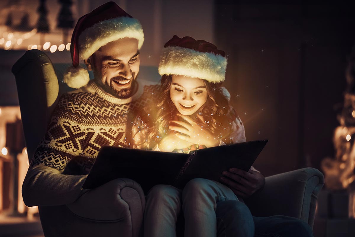 Vater liest mit Tochter Weihnachtsgedichte in Buch