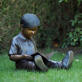 Kleiner Junge sitzt im Gras und liest Buch - Bronzestatue...
